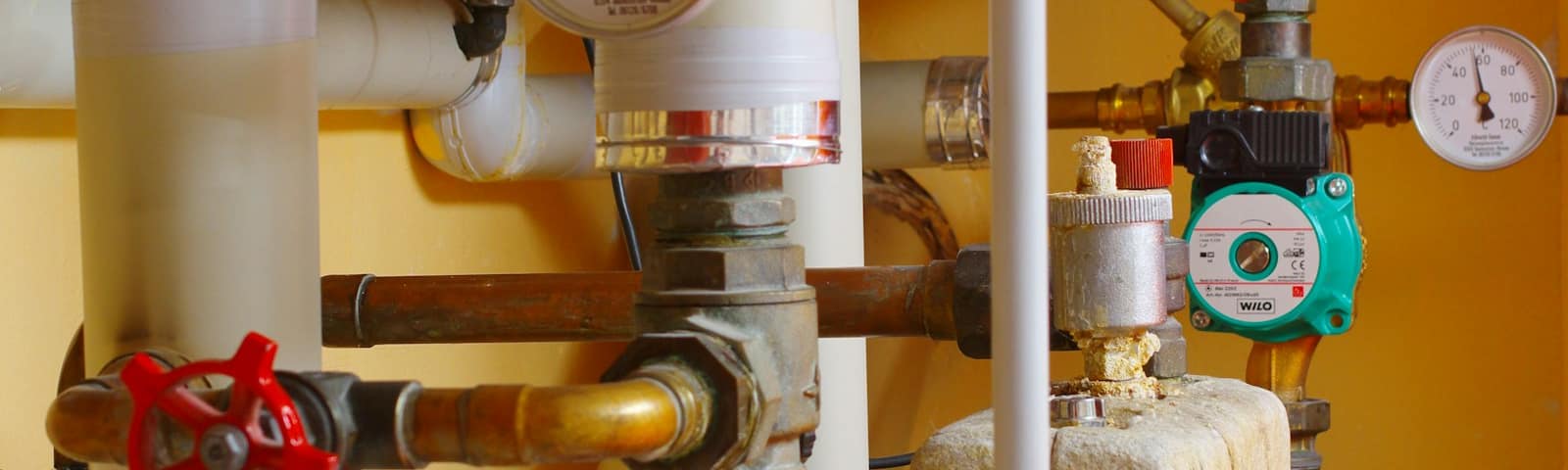 Water heater pipes and pressure gauges in a home utility room